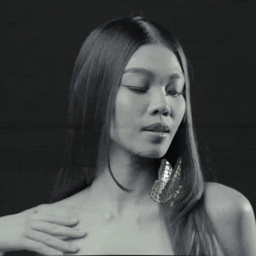 a black and white photo of a woman with long hair and a butterfly on her shoulder .