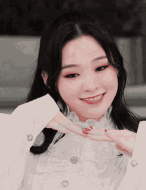 a woman with red nails is wearing a white shirt and smiling .
