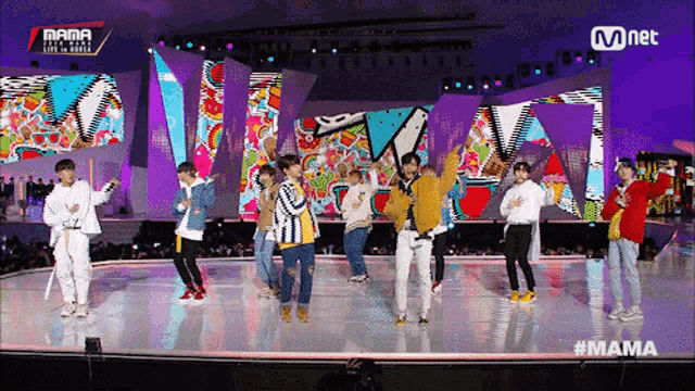a group of young men are dancing on a stage in front of a mnet banner