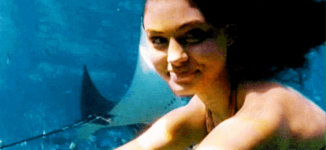 a woman is swimming underwater with a stingray behind her .