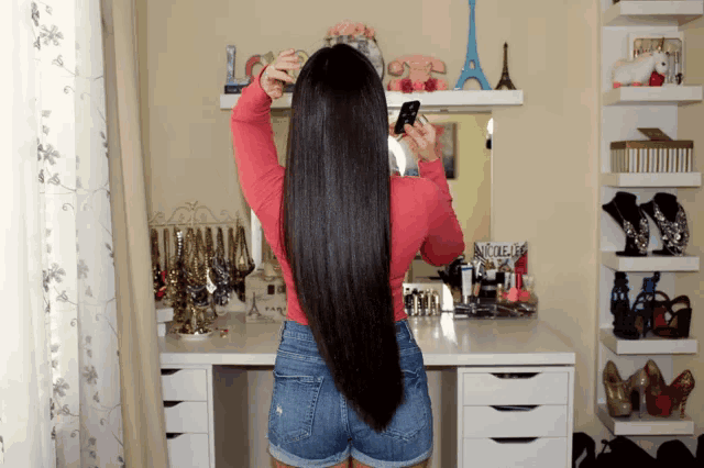 a woman taking a picture of herself in front of a vanity with a sign that says " nouveau " on it