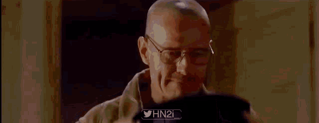 a bald man is holding a hat in his hand and looking through it .