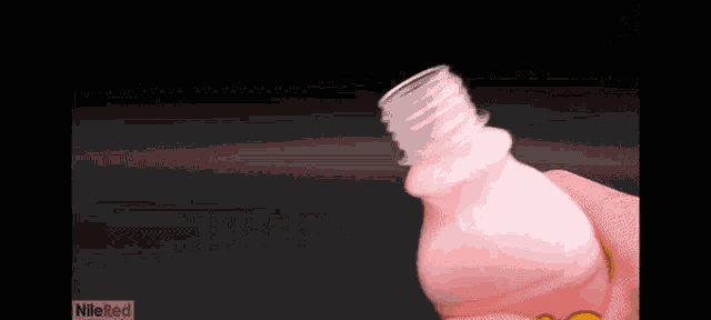 a person is holding a pink plastic bottle with the word nile ked on the bottom