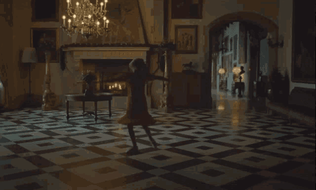 a woman in a red dress stands in a room with a checkered floor and a fireplace