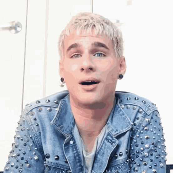 a young man wearing a denim jacket with studs on the sleeves
