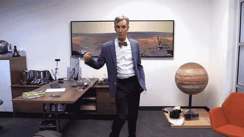 a man wearing a suit and bow tie is dancing in an office