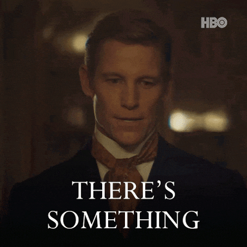 a man in a suit and tie is standing in front of a sign that says " there 's something "
