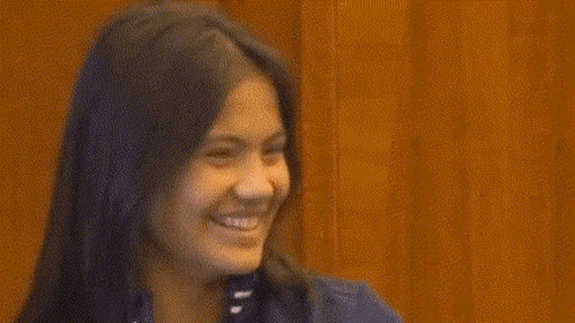 a woman with long hair is smiling and making a funny face .