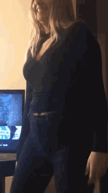 a woman in a black top and jeans is standing in front of a television