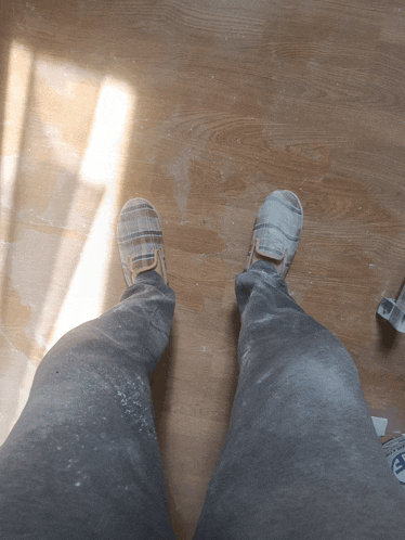 a person standing on a wooden floor wearing a pair of shoes that say ' converse ' on them