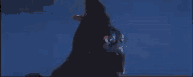 a close up of a person standing in the dark with a blue background .