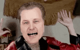 a man in a red leather jacket is making a funny face and waving his hands .