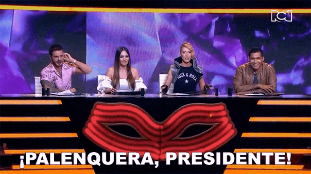 a group of people are sitting at a table with a mask on it and a sign that says palenquera presidente