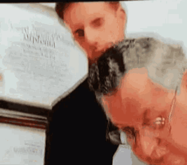 a man is licking another man 's face while looking at a certificate