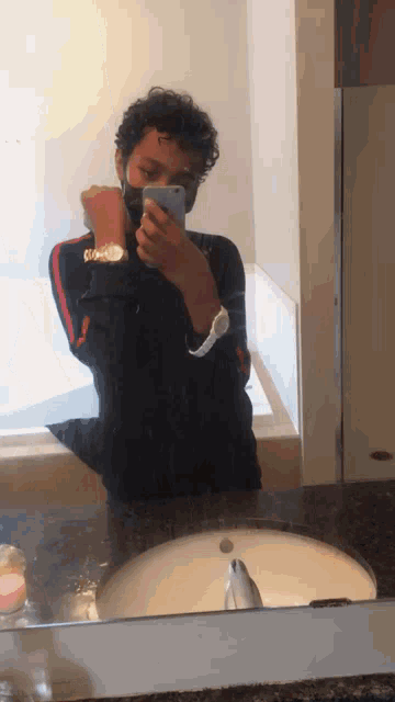a young man wearing a mask takes a picture of himself in a bathroom mirror
