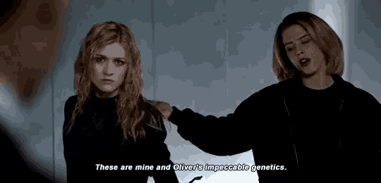two women are standing next to each other in a dark room and one of them is talking .