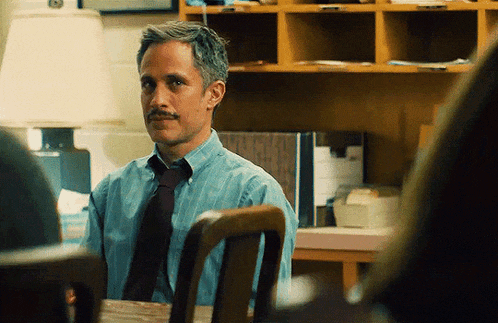 a man with a mustache is sitting at a table looking at something