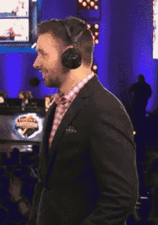 a man in a suit and headphones stands in front of a sign that says ' champions ' on it