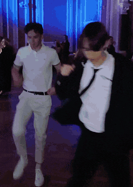 two men are dancing together in a dark room with blue lights