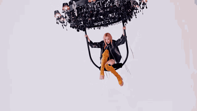 a woman in a black jacket and yellow boots is sitting on a black swing