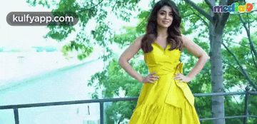 a woman in a yellow dress is standing on a railing .