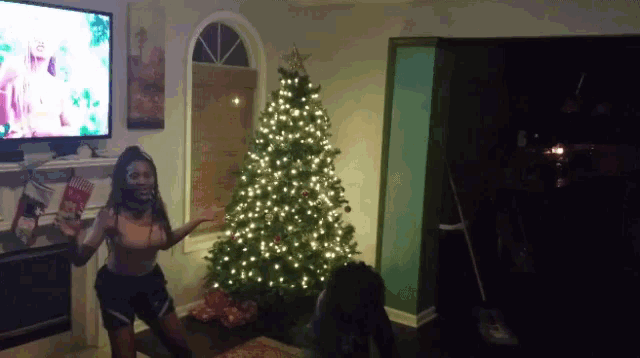 a woman standing in front of a christmas tree holding a book that says christmas
