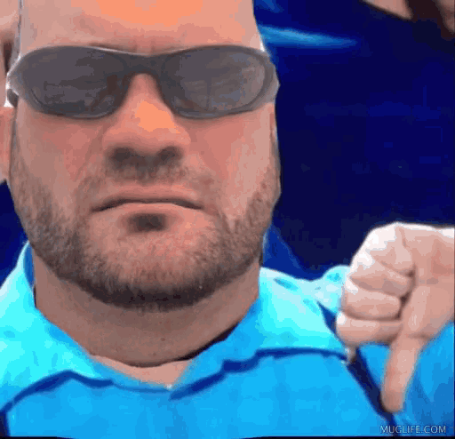 a man wearing sunglasses and a blue shirt giving a thumbs down sign