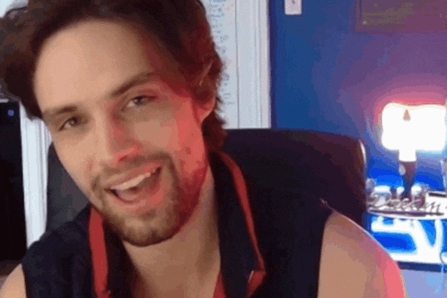 a man with a beard is smiling in front of a blue wall