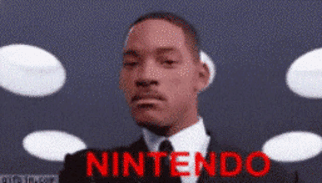 a man in a suit and tie is standing in front of a nintendo sign