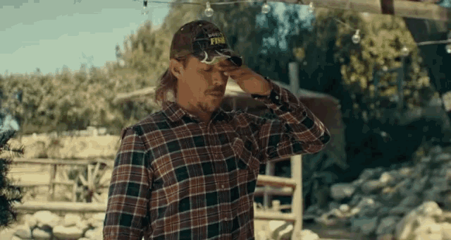 a man in a plaid shirt and a hat that says ' king ' on it