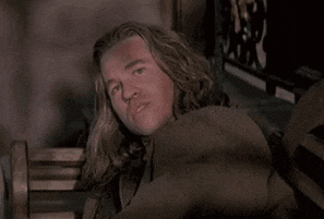 a man with long blonde hair is smiling while laying on a bench