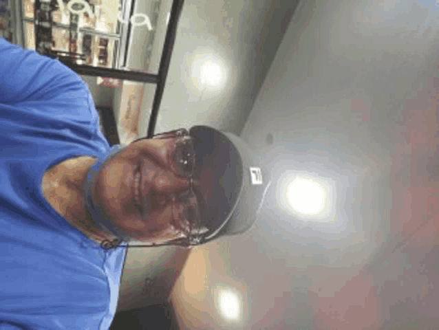 a man wearing a blue shirt and a black hat with the letter f on it