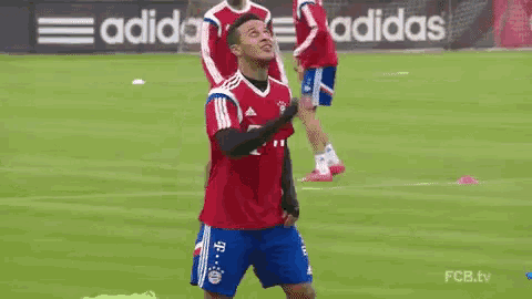 a man in a red t-mobile jersey is standing on a soccer field holding a soccer ball