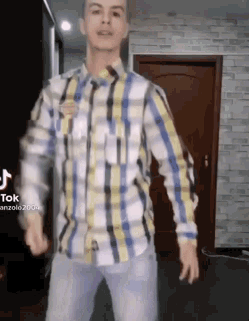 a man in a plaid shirt is dancing in front of a door .