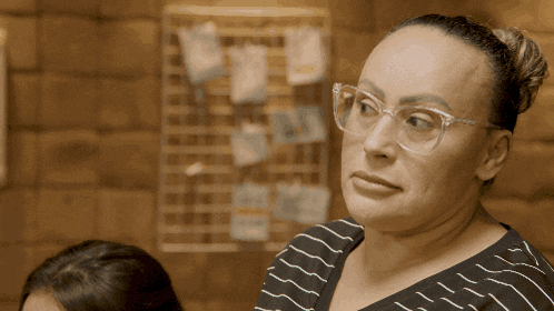 a woman wearing glasses and a striped shirt looks at something