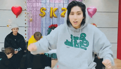 a young man wearing a hoodie is dancing in front of a group of people .