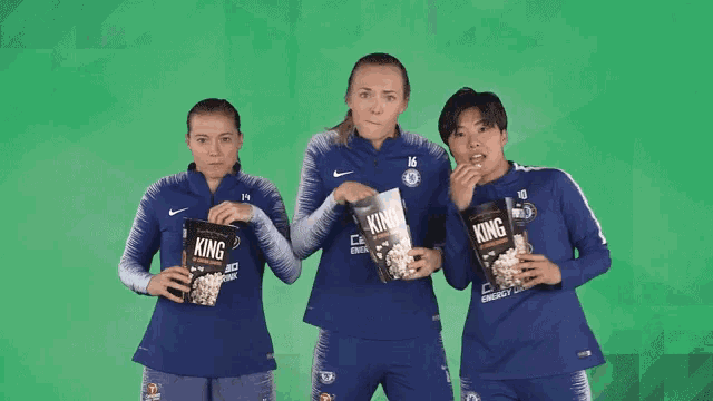 two female soccer players holding king popcorn in their hands