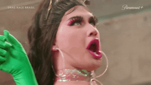 a drag queen is wearing green gloves and pink makeup