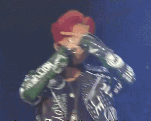 a man with red hair is singing into a microphone with rebellion written on his sleeves .