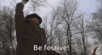 a man in a suit and hat is raising his fist in the air and saying `` be festive ! ''