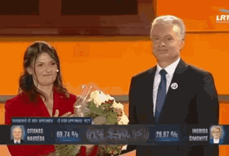 a man in a suit and tie is standing next to a woman holding flowers
