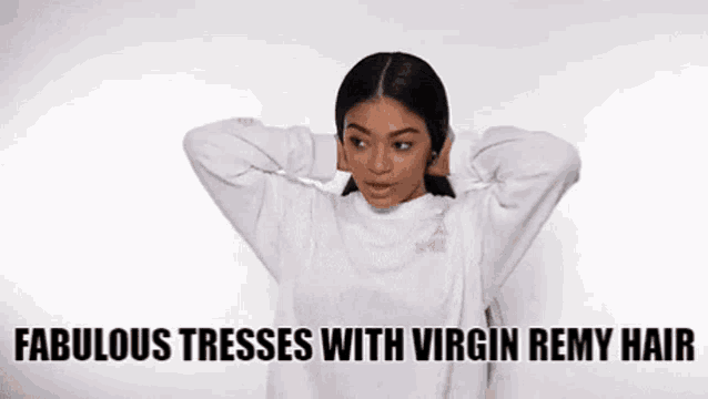 a woman is wearing a white sweater and holding her hair in her hands .