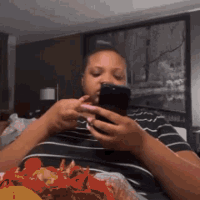a woman sitting on a bed looking at her phone