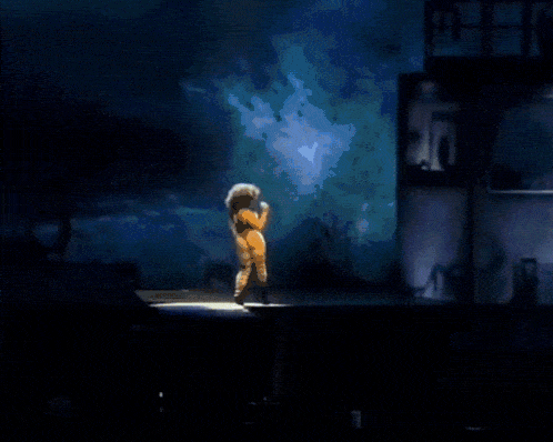 a woman in a yellow outfit stands on a stage