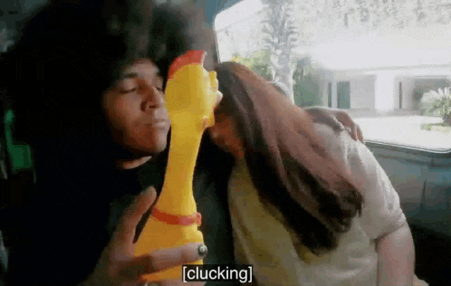 a man is kissing a woman on the cheek while holding a toy chicken with the word clucking written on it