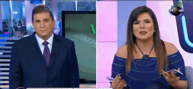 a man in a suit and tie stands next to a woman in a blue dress on a tv show