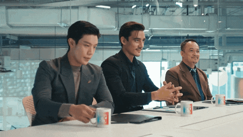three men are sitting at a table with coffee mugs that say mcdonalds on them