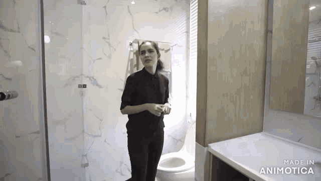 a woman standing in a bathroom with the words made in animatica on the bottom right