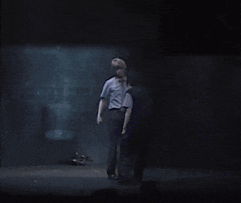 a man in a blue shirt is standing in the dark
