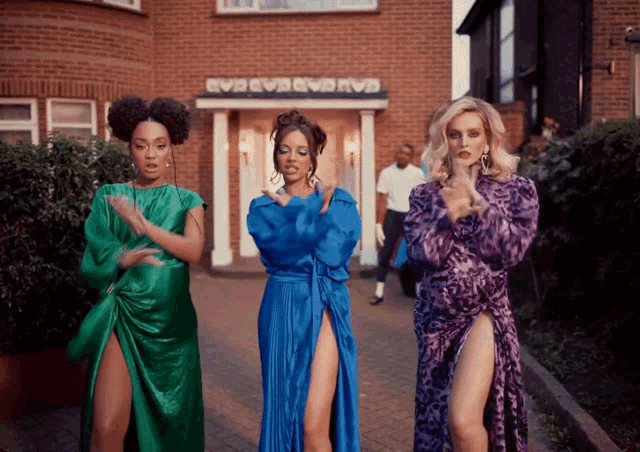 three women are dancing in front of a brick building that says evb evb evb